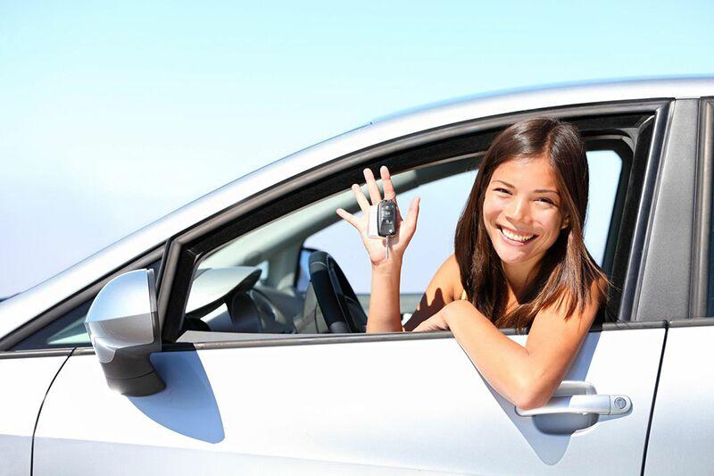 teen girl leaning out of car window with keys in hand
